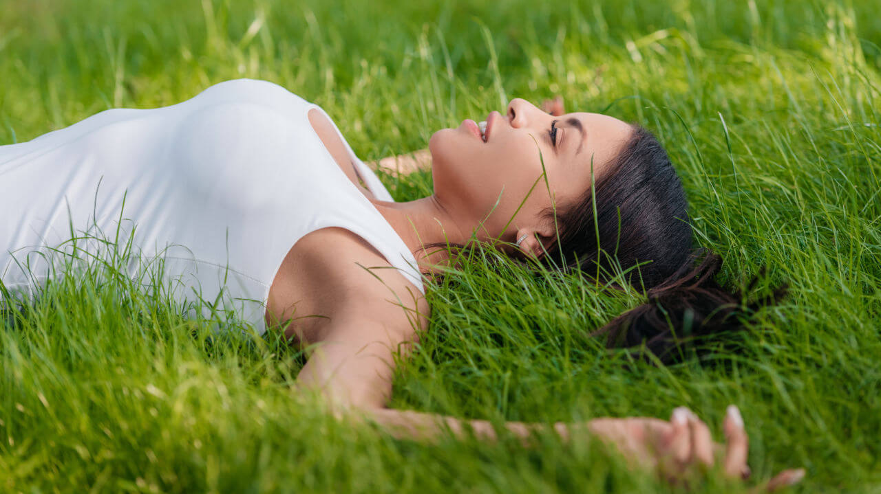 Imagen de una mujer acostada en el pasto verde